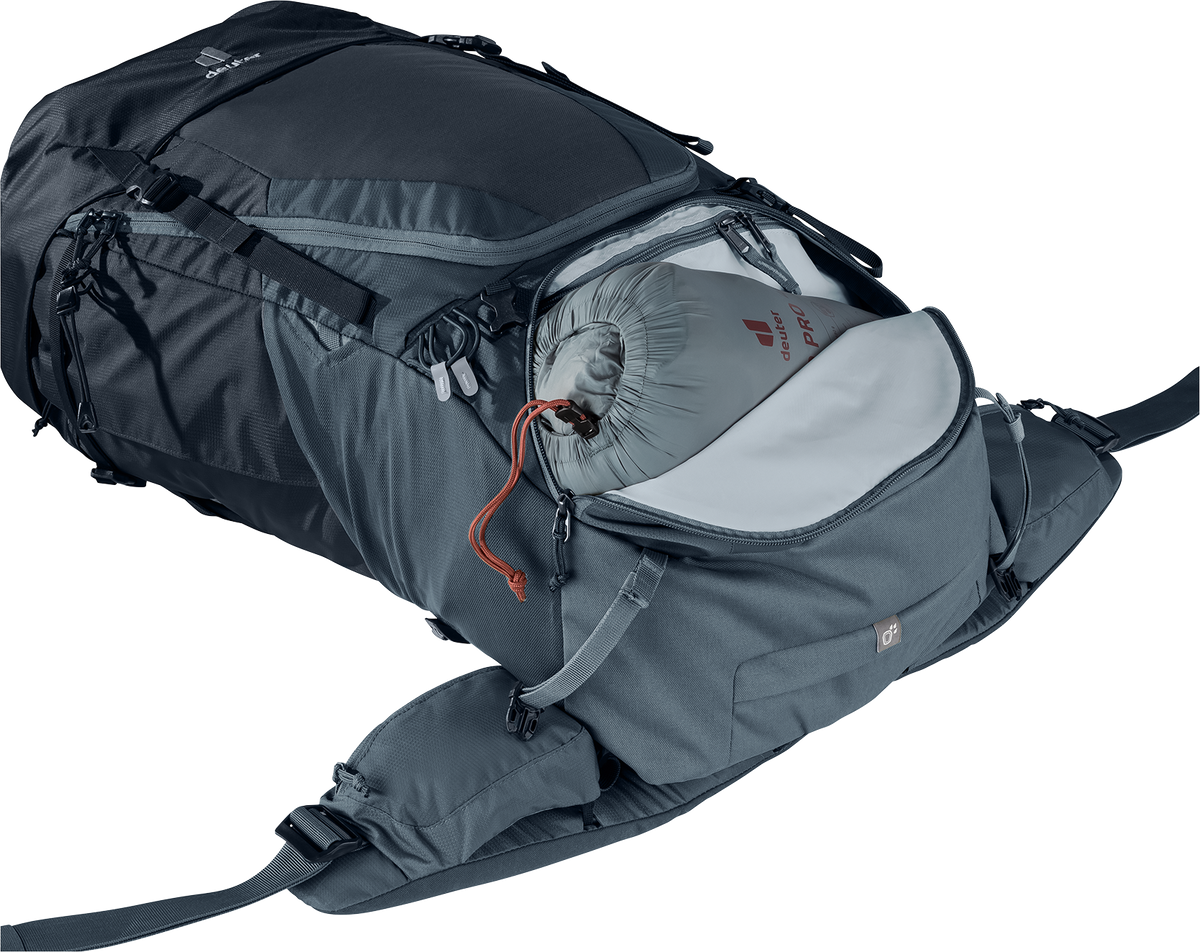 Ryggsäcken Deuter Futura Air Trek 60+10 liggande ner med det nedre facket öppet, där en packpåse med Deuter-logga är nedpackad. Facket visar ryggsäckens volym och åtkomstmöjligheter.
