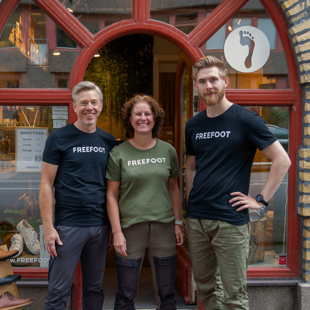 Tre medarbetare från Freefoot står framför butikens entré och ler mot kameran. De bär Freefoot‑tröjor och utstrålar en välkomnande känsla.