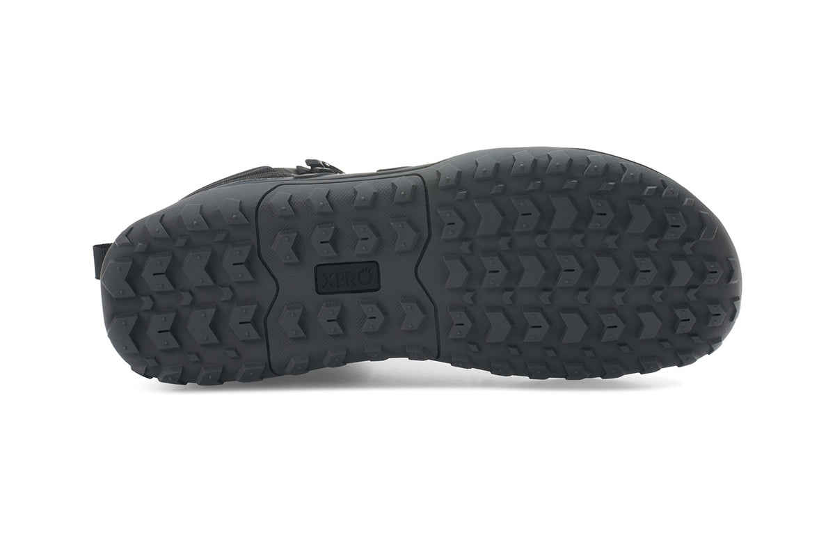 Undersidan av Xero Shoes Scrambler Mid WP Black – vattentät barfotakänga i svart med grovt mönstrad yttersula, bred tåbox och lätt konstruktion för terräng och vandring i alla väder.