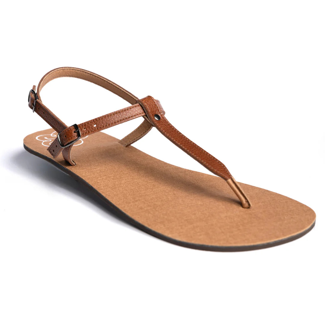 Produktbild av minimalistisk barfotasko från Lonnies i modellen Warm Amber. Sandalen har en tunn Y-formad rem i brunt läder, justerbart hälspänne och en platt, naturfärgad sula. Fotograferad i sned vinkel mot vit bakgrund för att tydligt visa design och passform