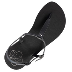 Produktbild på Lonnies sandaler Lux Little Black sedd uppifrån. Den minimalistiska barfotaskon har svarta remmar i T-design, ett justerbart spänne och en slät svart sula med Lonnies logotyp tryckt i hälen. Designad för barfotakänsla med stilren komfort.