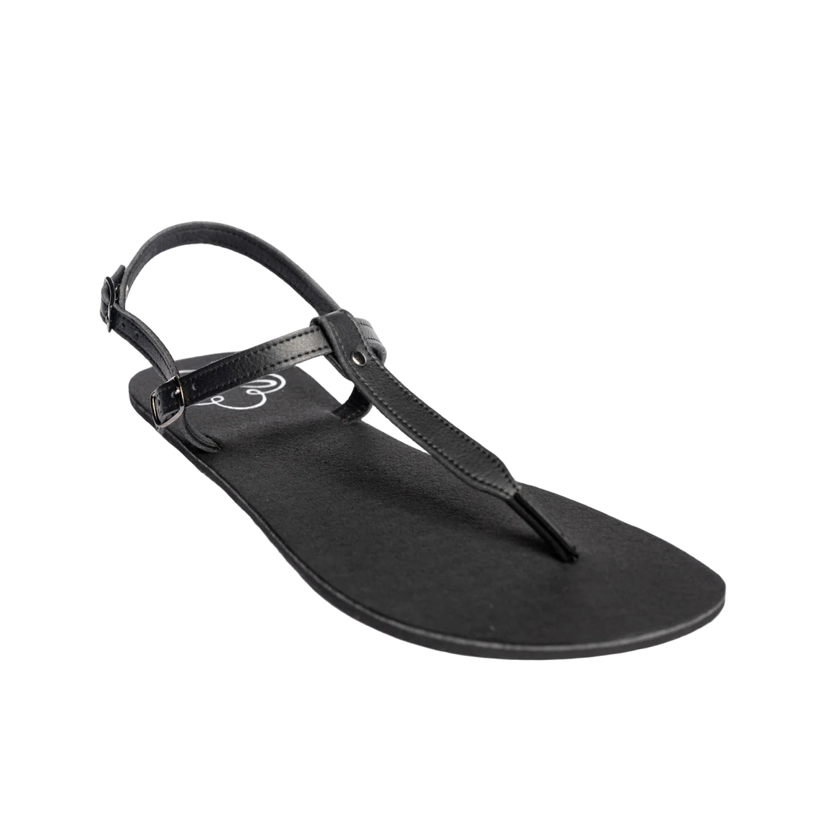 Produktbild på Lonnies barfotasko i modellen Lux Little Black, fotograferad i sned vinkel framifrån. Sandalen har tunna svarta remmar med spänne, T-remdesign och en minimalistisk svart sula. Perfekt för barfotakänsla med stilren look